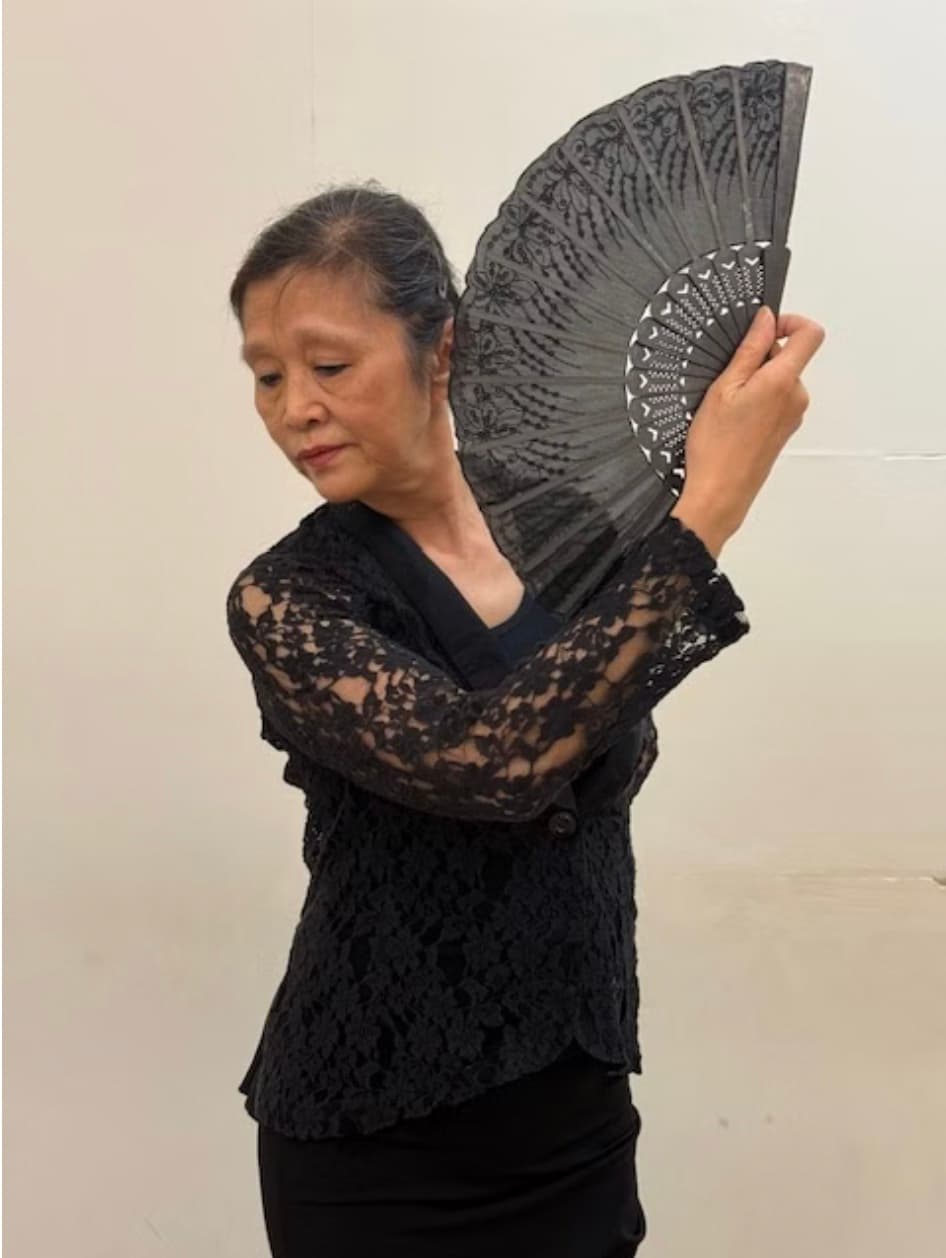 Shun Clayton striking a flamenco pose with a black lace fan